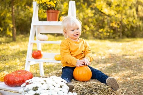 Premium Photo | Baby boy with pumpkins in autumn park background