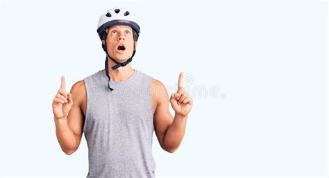 Young Handsome Man Wearing Bike Helmet Amazed And Surprised Looking Up