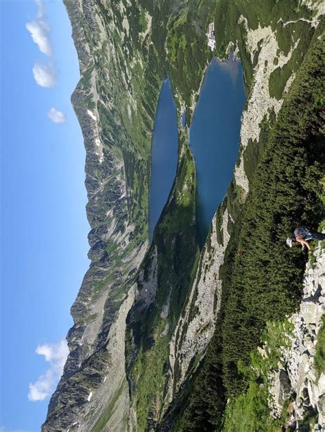 Two People Are Standing On The Edge Of A Mountain