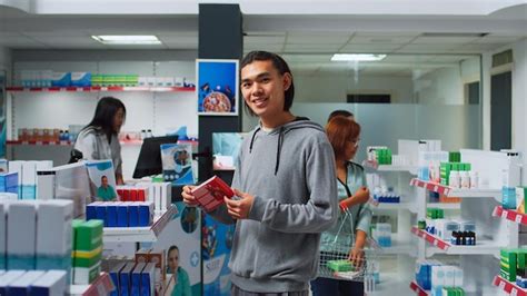 Cliente asiático revisando cajas de pastillas en los estantes de la