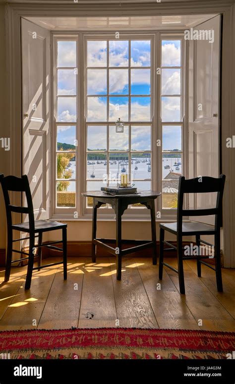 Two Empty Chairs And A Round Table Inside A Cottage Looking Out Through