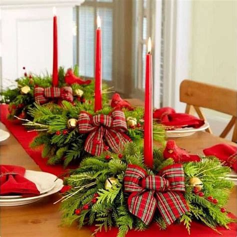 A Christmas Centerpiece With Candles And Greenery On A Dining Room Table Decorated For The