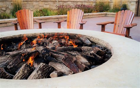 Adirondack chairs by the fire pit with flames | More Pro Inc.