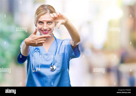 Belle jeune femme blonde infirmière médecin chirurgien sur fond isolé du châssis en souriant