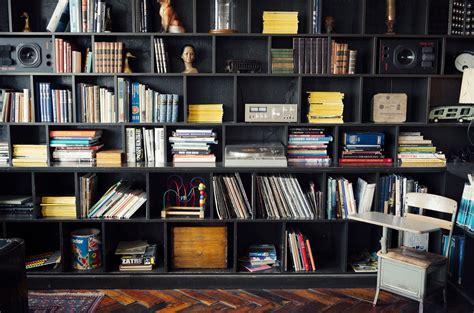На книжной полке стоят книжные тома в беспорядке - фото