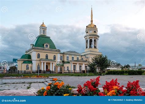 Yellow Church In The Square In The Foreground Red Flowers Stock Photo