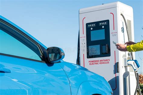 Man Using An App On A Phone To Connect A Car To An Electric Vehicle Ev