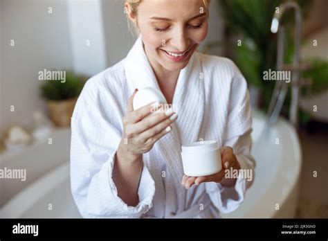 Gros plan de la femme blonde joyeuse sourit dans la robe ouverture crème ou lotion du corps