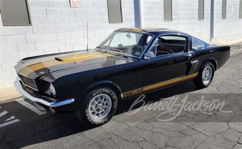 A Black And Gold Mustang Parked In Front Of A Building