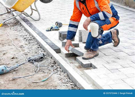 Un Trabajador Coloca Losas De Pavimento Con Un Martillo De Caucho En