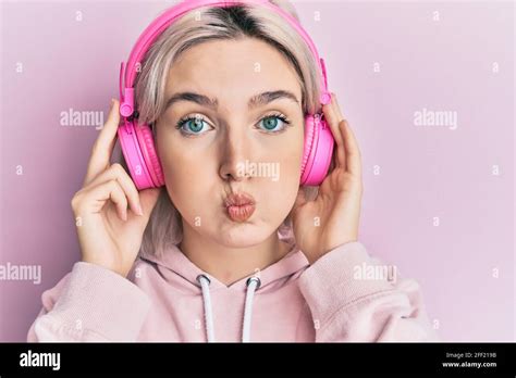 Jeune Fille Blonde Coutant De La Musique En Utilisant Des Couteurs Puffant Les Joues Avec Le