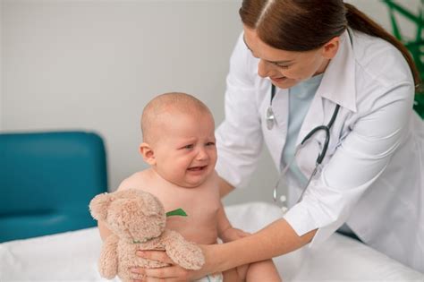 Premium Photo Caring Doctor Giving A Toy To A Crying Baby