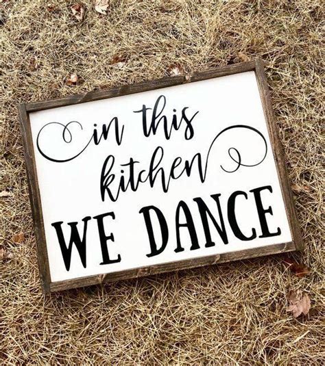 A Sign That Says In This Kitchen We Dance On The Ground With Dry Grass