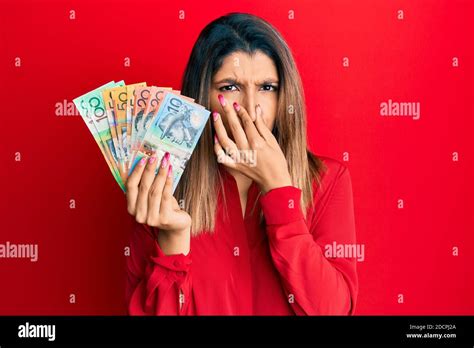 Beautiful Brunette Woman Holding Australian Dollars Smelling Something Stinky And Disgusting