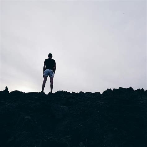 Premium Photo Rear View Of Man Standing On Rocks Against Sky