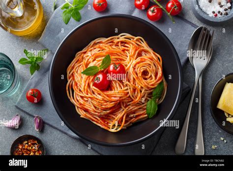 Pasta Spaghetti With Tomato Sauce In Black Bowl On Grey Stone