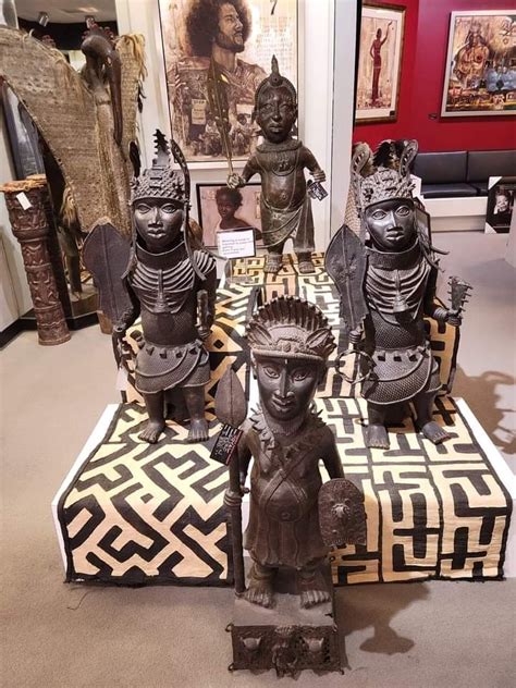 Some Statues On Display In A Room With Red Walls And Pictures Hanging