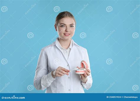 Dental Assistant With Jaws Model And Toothbrush On Light Blue