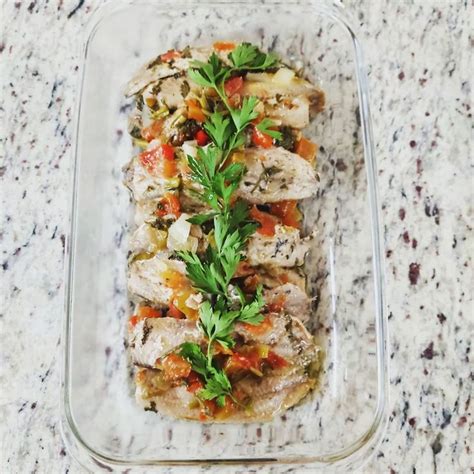 A Glass Casserole Dish Filled With Meat And Vegetables On A Marble