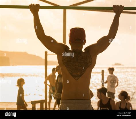 Rear View Of Muscular Man With Back Tattoo Doing Pull Upschin Ups On