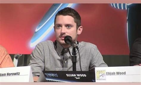 Two Men Sitting At A Table With Microphones In Front Of Them And One