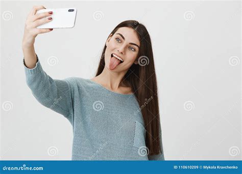 Attractive And Trendy Brunette Raising Hand While Taking Selfie On Smartphone Sticking Out