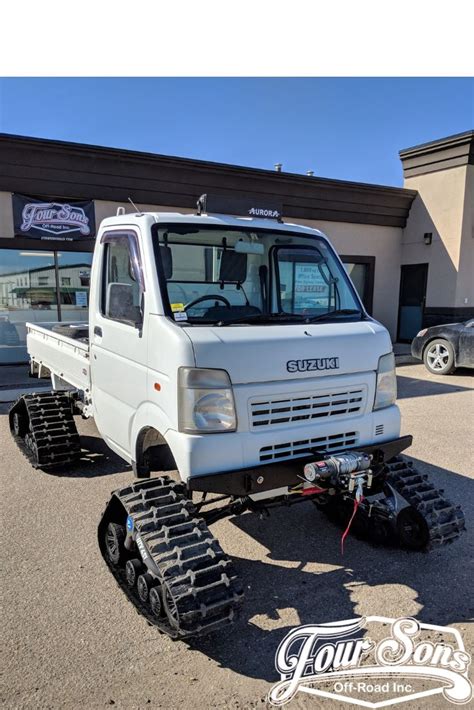 a white truck parked in front of a building with snow tracks on it's tires