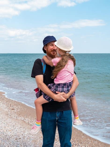 Familia feliz padre hija abrazándose en el paisaje marino padre barbudo