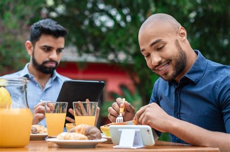 Premium Photo Black Gay Couple Having Breakfast And Looking At Mobile Outside In The Garden Person