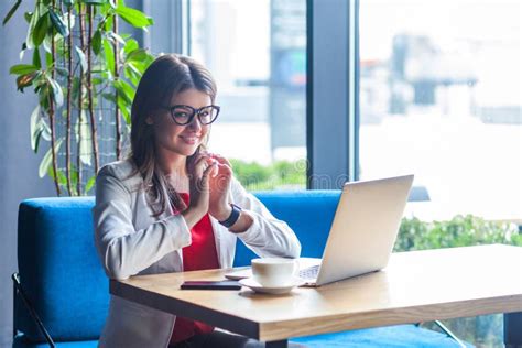 Strålningskänslig Stilfull Brunette Ung Kvinna I Glasögon Som Sitter Och Tittar På Kameran Med