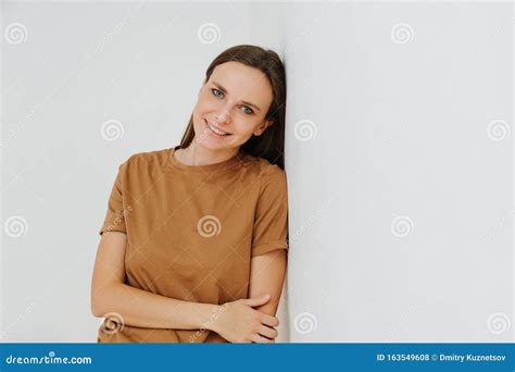 Portrait Of A Smiling Woman Leaning On The Wall With One Hand Holding