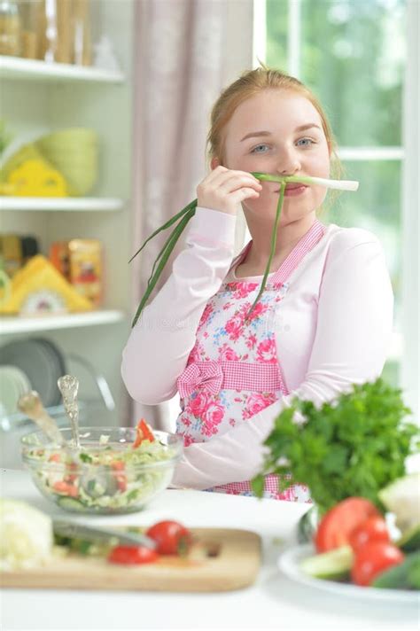 Portrait Of Cute Teen Girl Preparing Fresh Salad On Kitchen Table Stock