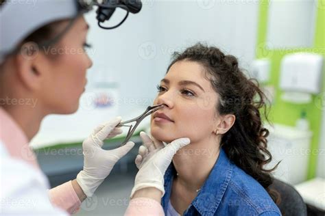 Otolaryngology concept. Positive woman otorhinolaryngologist checking nose with otoscope of his ...