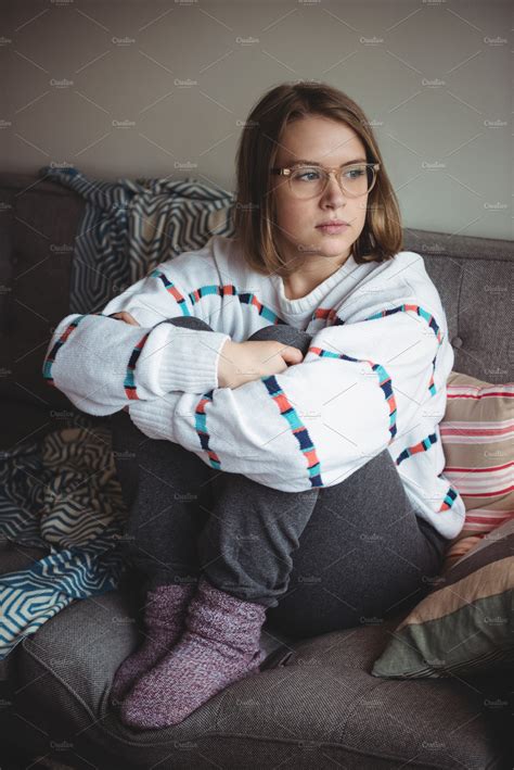 Thoughtful Woman Sitting And Hugging Her Knees In Living Room Stock