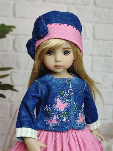 A Doll With Blonde Hair Wearing A Blue Dress And Pink Hat