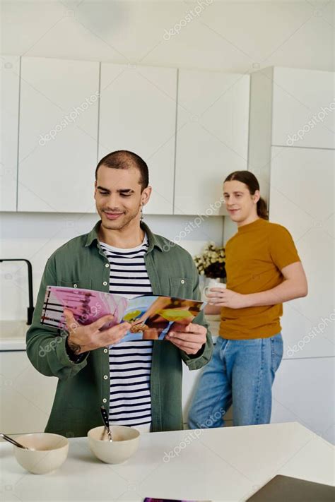 Una Joven Pareja Gay Pasa Tiempo Juntos En Su Cocina Moderna Uno Navegando En Una Revista