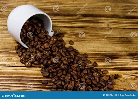 Roasted Coffee Beans Spill Out Of Cup On Wooden Table Stock Image