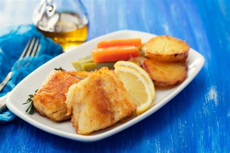 Fried Cod Fish With Lemon And Vegetables On White Plate Stock Image