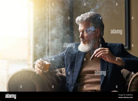 Pensive Stylish Mature Businessman Holding Cigar And A Glass Of Whisky