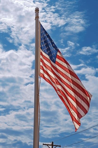 Premium Ai Image American Flag Waving Against A Blue Sky Backdrop