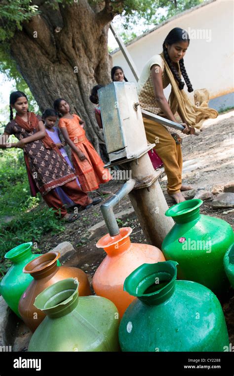 Rural Indian Village Girl Filling Water Pots From A Communal Water Pump