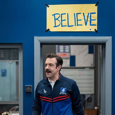 A Man Standing In Front Of A Blue Door With A Yellow Sign Above It That