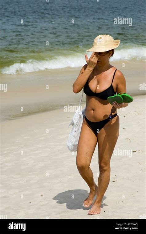 Stock Photo Of A Middle Age Woman Wearing Bikinis And Hat Walking On