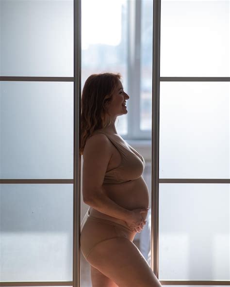 Premium Photo A Pregnant Woman In Nude Lingerie Stands In Profile Between Folding Doors
