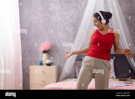 Teenage Girl Listening Music On Headphones And Dancing In Bedroom Stock