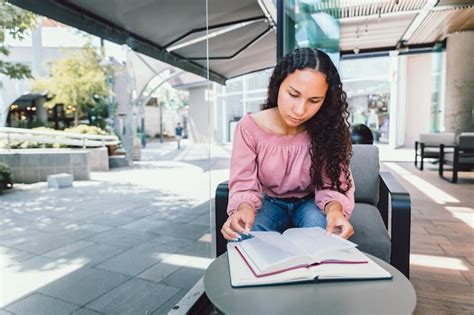 Estudante universitária latina sentada e estudando para um exame do lado de fora de um café