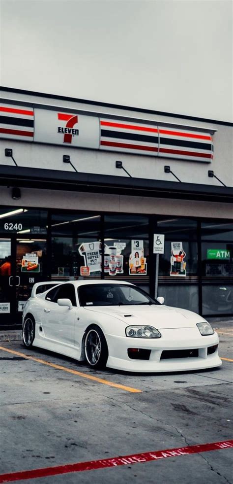 A White Sports Car Parked In Front Of A Fast Food Restaurant On A