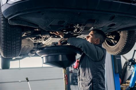 El trabajador de un taller mecánico está drenando aceite del motor del