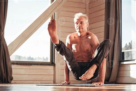 Senior Man With A Naked Torso Practicing Yoga Classic Asana Training In Studio In Front Of A