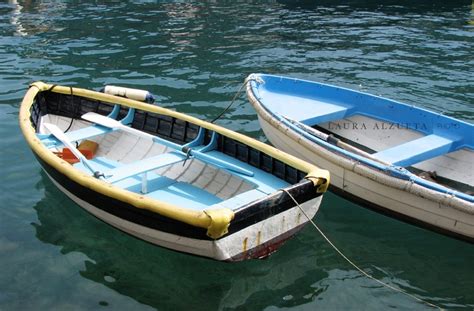 Two Small Boats Tied To The Side Of Each Other In Clear Blue Water With